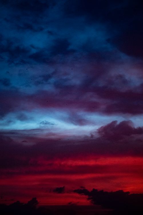 Free Vivid twilight sky displaying deep reds and blues with dramatic cloud formations. Stock Photo