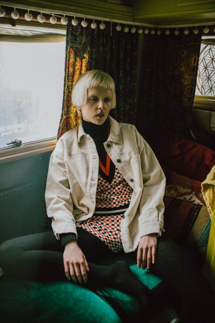 Fashionable caucasian woman in a vintage van with retro decor, dressed in eclectic style.