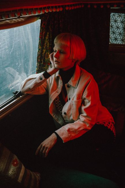 Blonde woman with short hair gazing out train window, deep in thought.