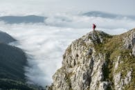 一名身着红色的徒步旅行者站在落基山脉被云层笼罩的山峰上
