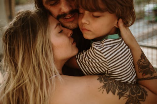 Close-Up Photo of a Family Hugging Each Other while Their Eyes are Closed