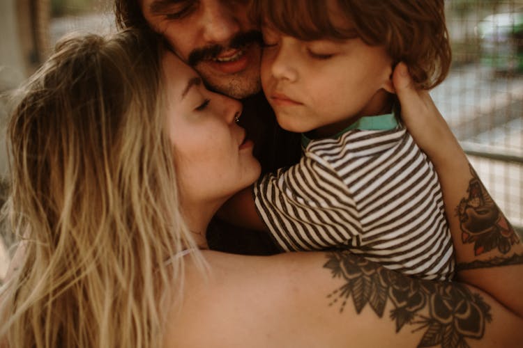 Close-Up Photo Of A Family Hugging Each Other While Their Eyes Are Closed