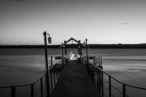 Grayscale Photo of Dock on Sea