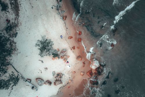 Free Aerial view of stone boulders scattered on sandy beach washing by foamy ocean Stock Photo