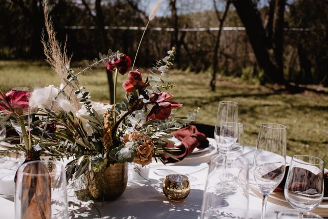 Table de mariage en extérieur avec centre de table fleuri et verrerie