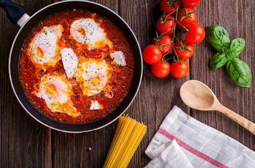 Free Black Frying Pan With Spaghetti Sauce Near Brown Wooden Ladle and Ripe Tomatoes Stock Photo