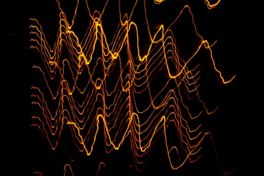 Long exposure of creative modern freezelight light painting with bright wavy lines creating patterns shining on black background in darkness