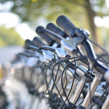 Close-up of bicycle handlebars in a row, showcasing a cycle stand for transportation.