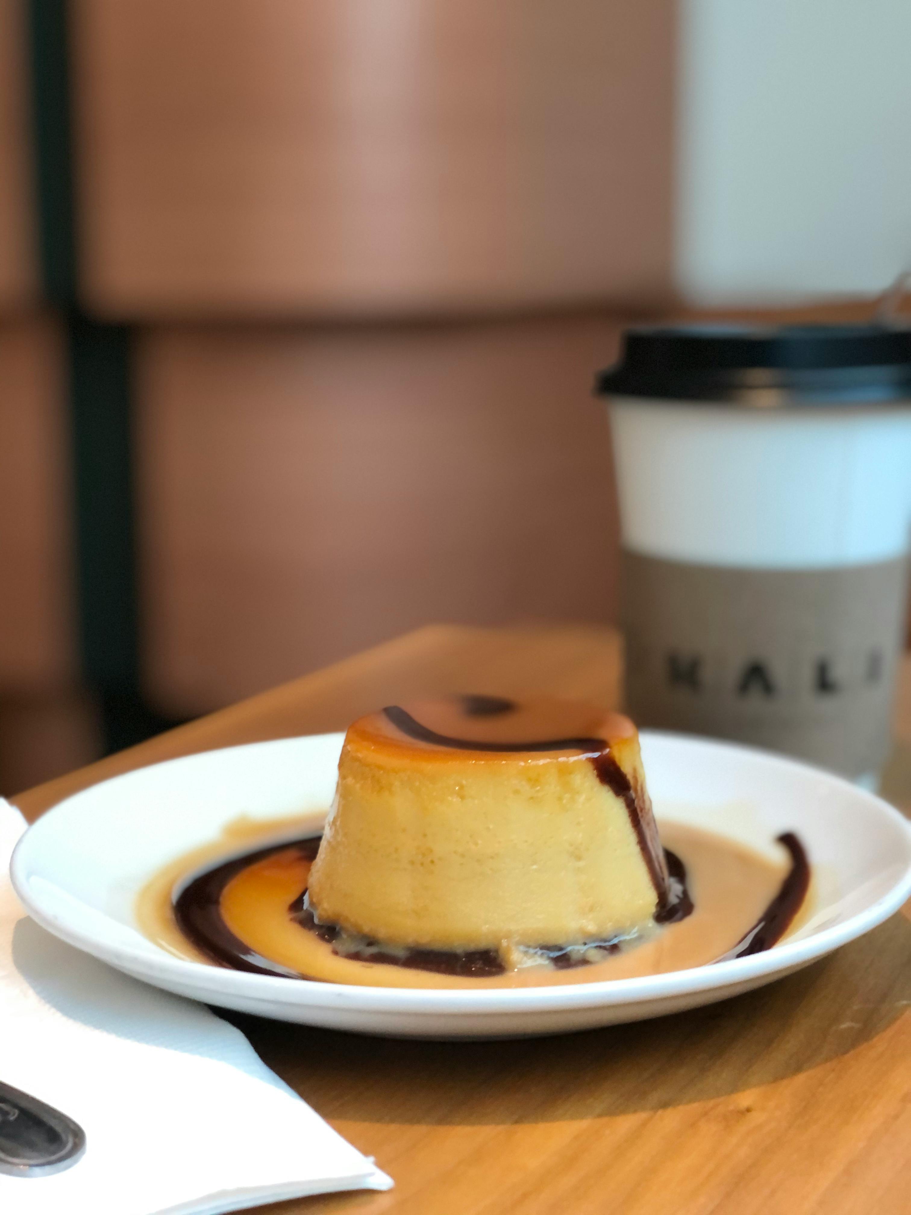 Caramel flan dessert on ceramic plate with coffee cup; perfect for a sweet indulgence.