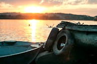 湖面宁静的日落中，小船与远处的游泳者构成了一幅平和的景象