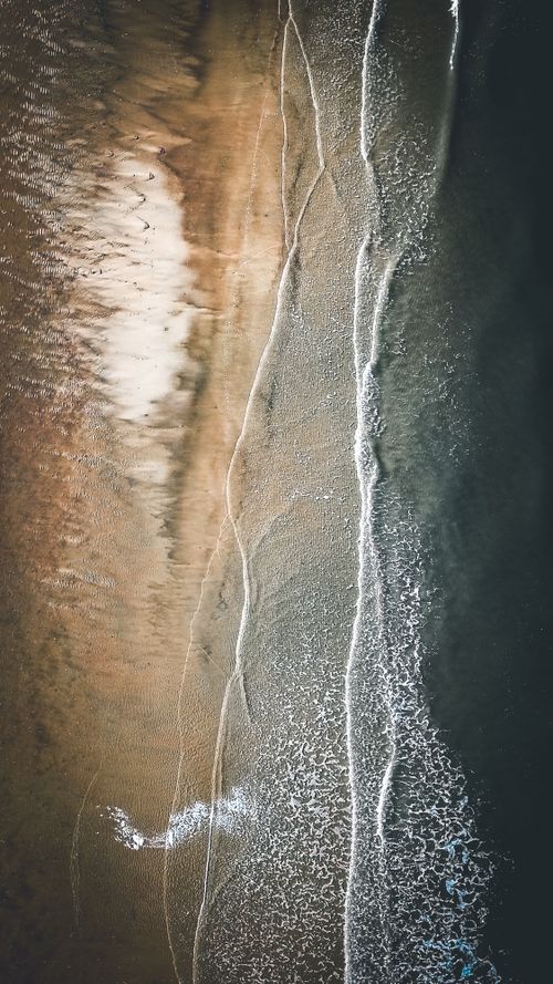Free Aerial top view of clear blue water of ocean rolling on sandy coastline Stock Photo
