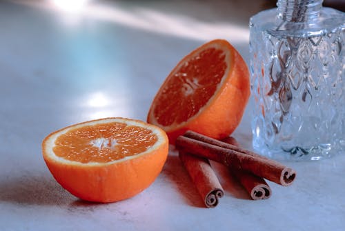 Cut ripe orange and cinnamon sticks against vase