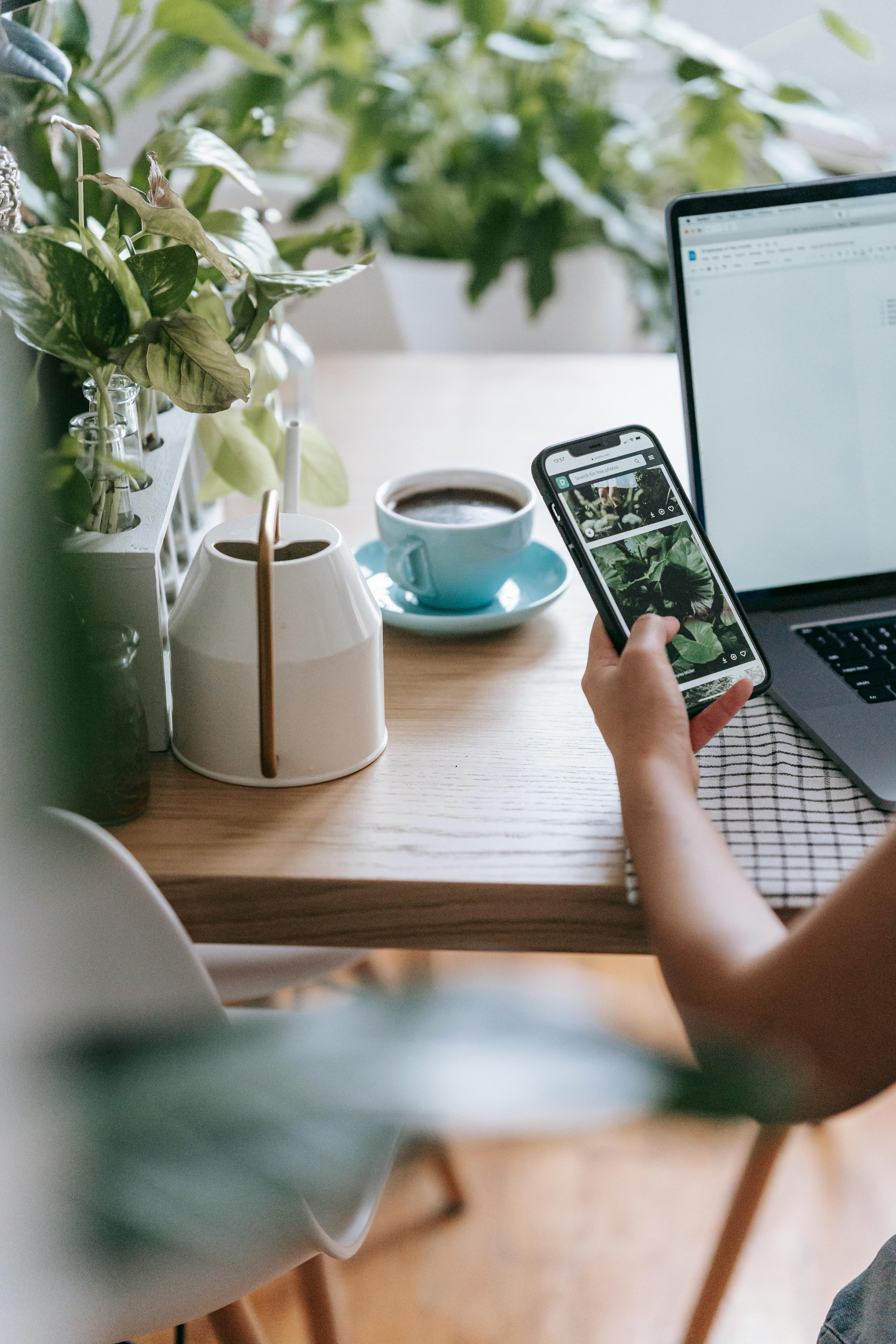 crop faceless person using laptop and smartphone in light room