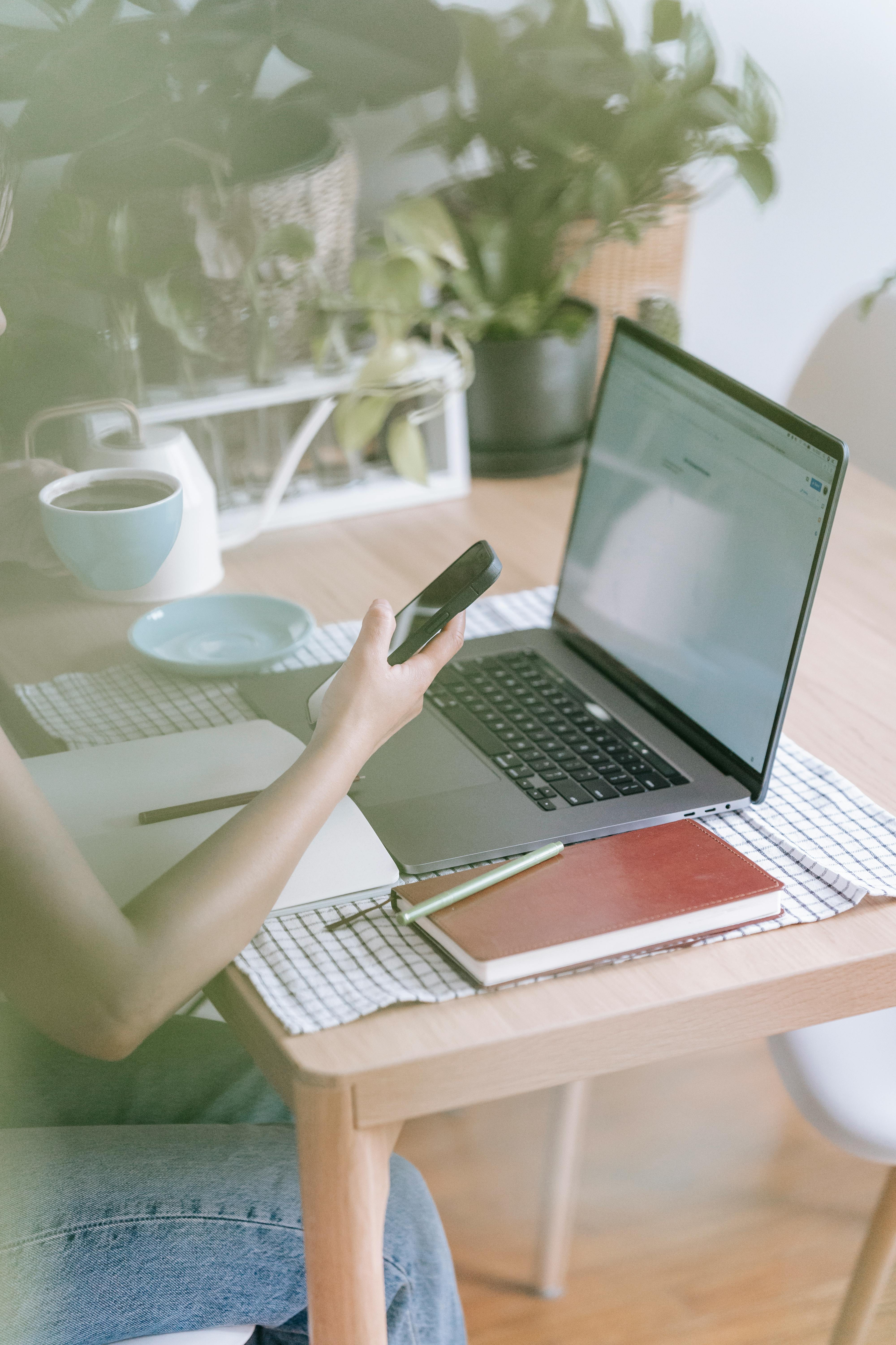 crop faceless woman using on laptop and smartphone at home