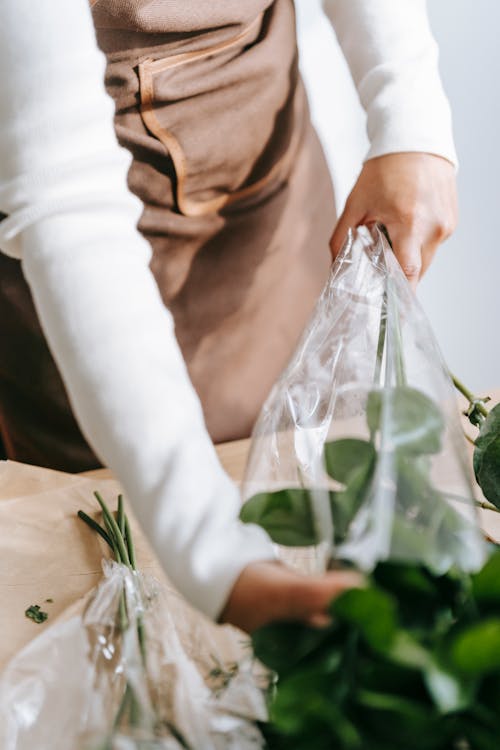 Woman wrapping flowers in plastic package