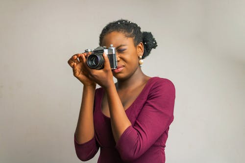 A Woman in Purple Long Sleeves Taking Photos Using a Digital Camera