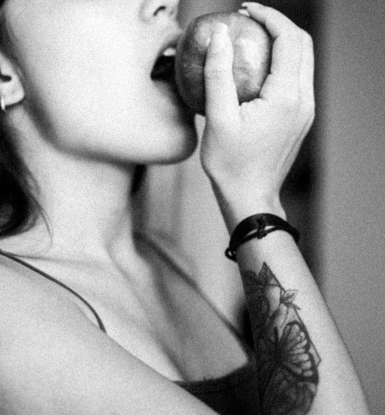 Grayscale Photo Of A Woman Biting An Apple