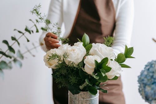Experienced florist arranging white roses with green stems