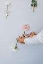 Crop florist making flower composition on white background