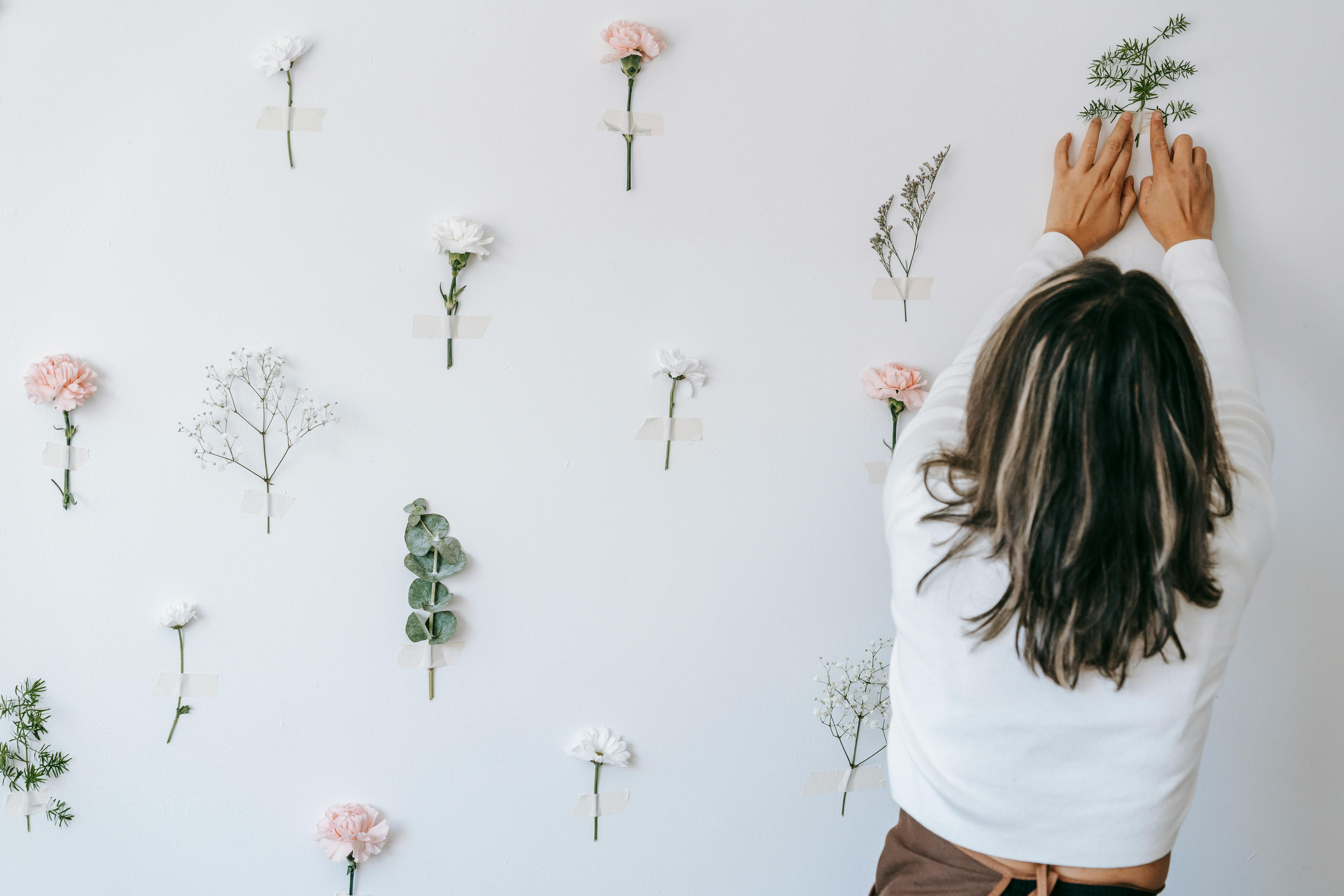 female florist making composition of tender flowers on white background