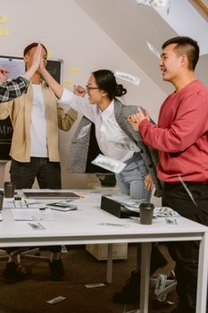 A dynamic office team celebrates success together with high fives and enthusiasm.