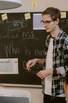 Young man presenting ideas at a creative meeting in casual office setting.