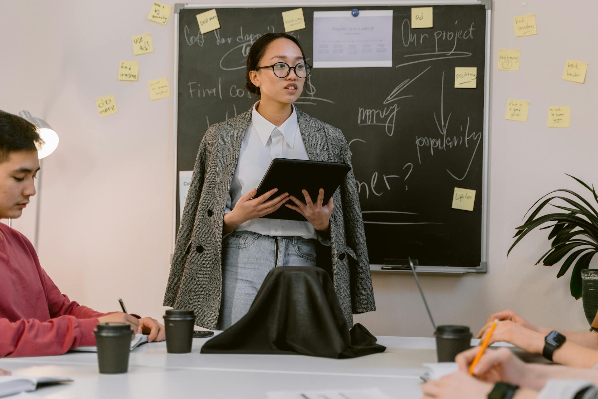 A young professional woman gives a presentation to coworkers in a modern office setting.