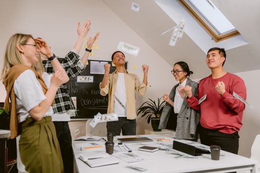 Diverse team excitedly celebrating success in a modern office setting.