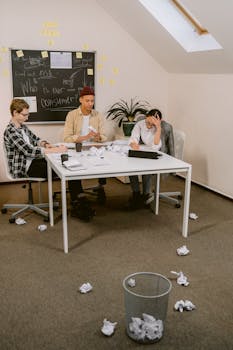 Three colleagues brainstorming ideas in a cluttered office environment.