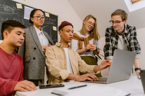 Free A diverse team of young professionals brainstorming with a laptop in a modern office. Stock Photo