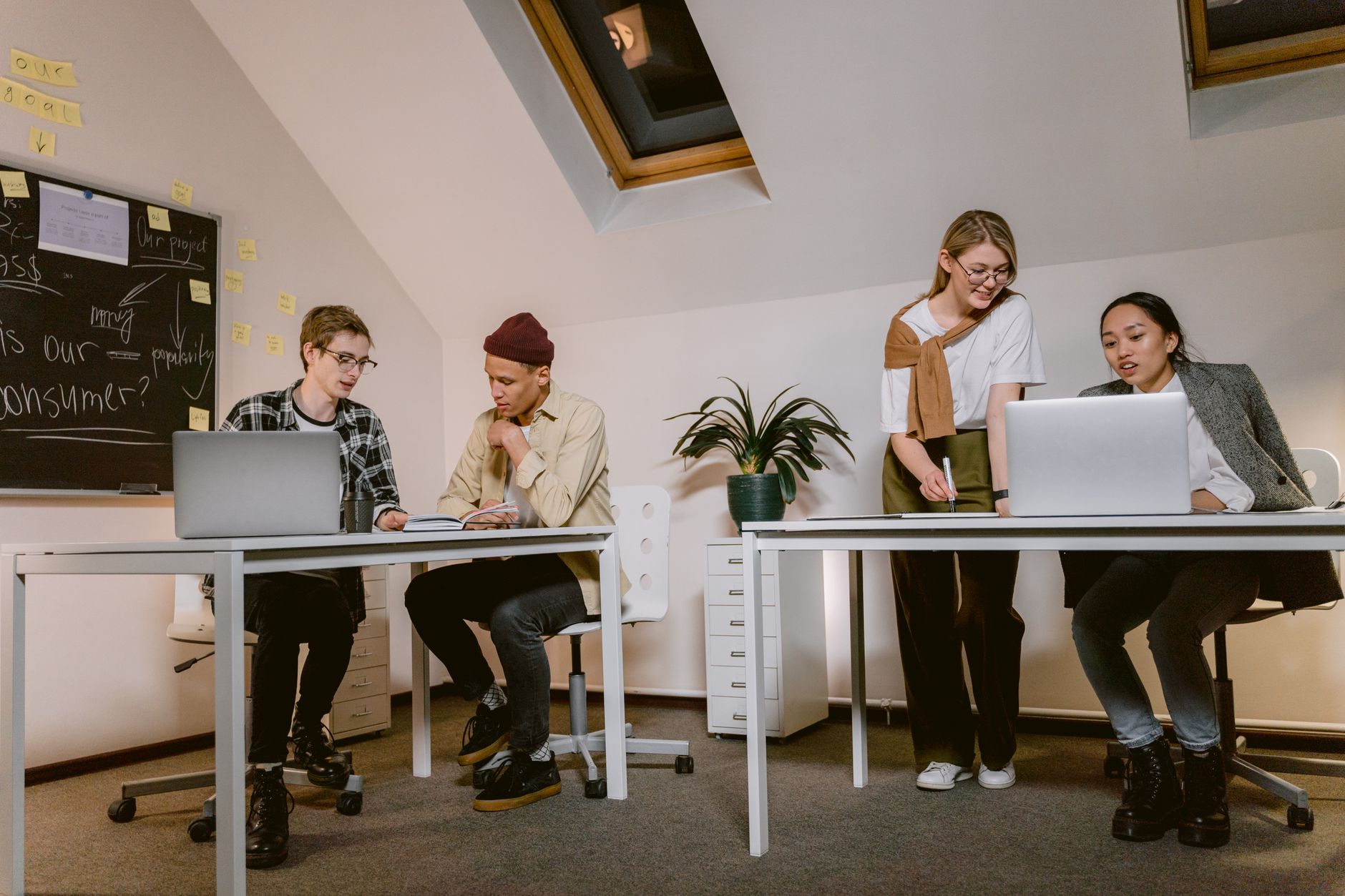 Young professionals brainstorm and work together at a modern office desk.