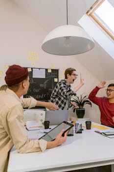 Young professionals in a creative meeting, celebrating teamwork with high-fives in a modern office setting.