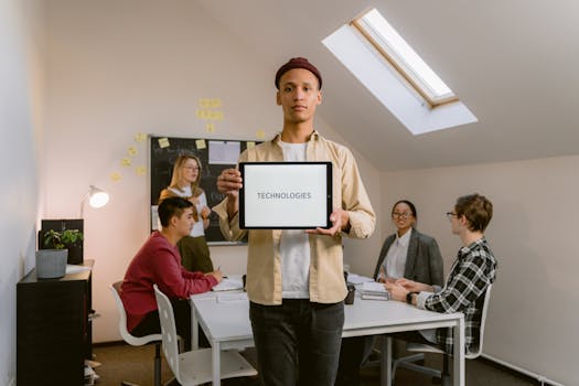 A group of colleagues in an office, collaborating on technology ideas over a laptop and tablets.