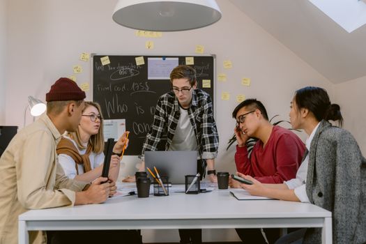 A diverse group of colleagues collaborating in a modern office setting with laptops and sticky notes.