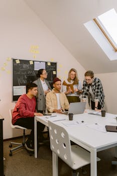 Group of young professionals collaborating at an office meeting with a laptop and notes.