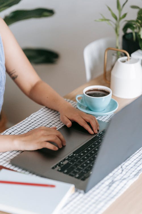 Woman working with laptop at table with coffee