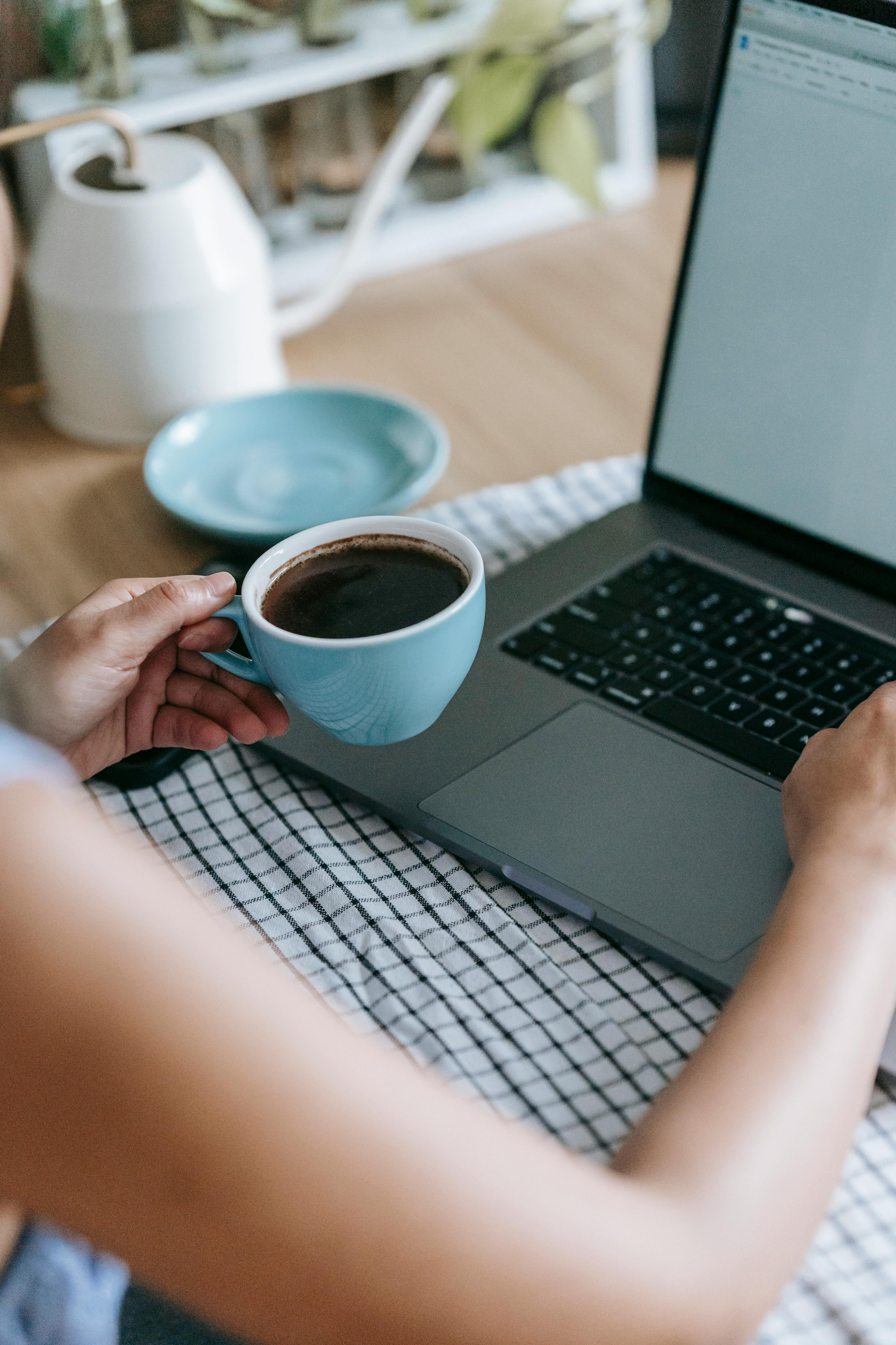 woman with strong coffee at table with laptop