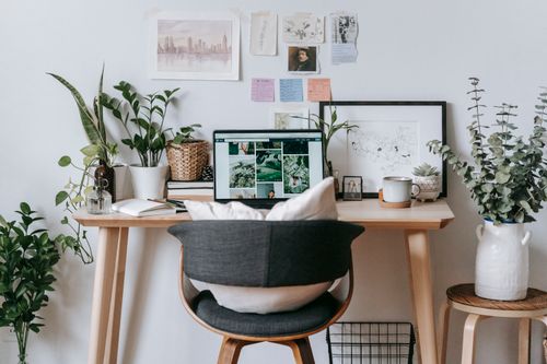 Free Modern workspace with comfortable gray chair with pillows and table with netbook near wall with stickers and pictures Stock Photo