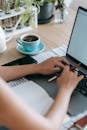 Woman working on project with laptop at table with coffee