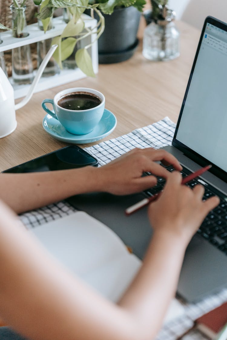 Woman Working On Project With Laptop At Table With Coffee