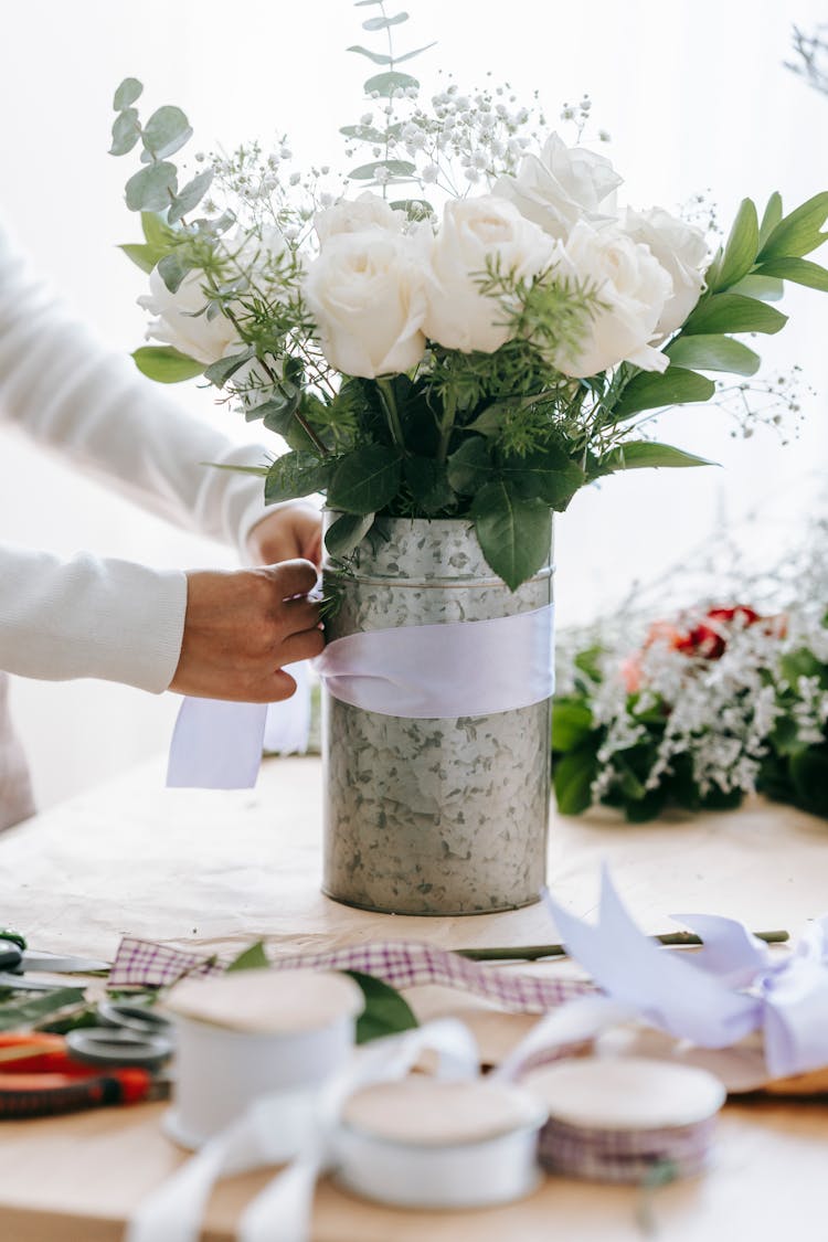 Florist Tying Ribbon On Bouquet Of Roses