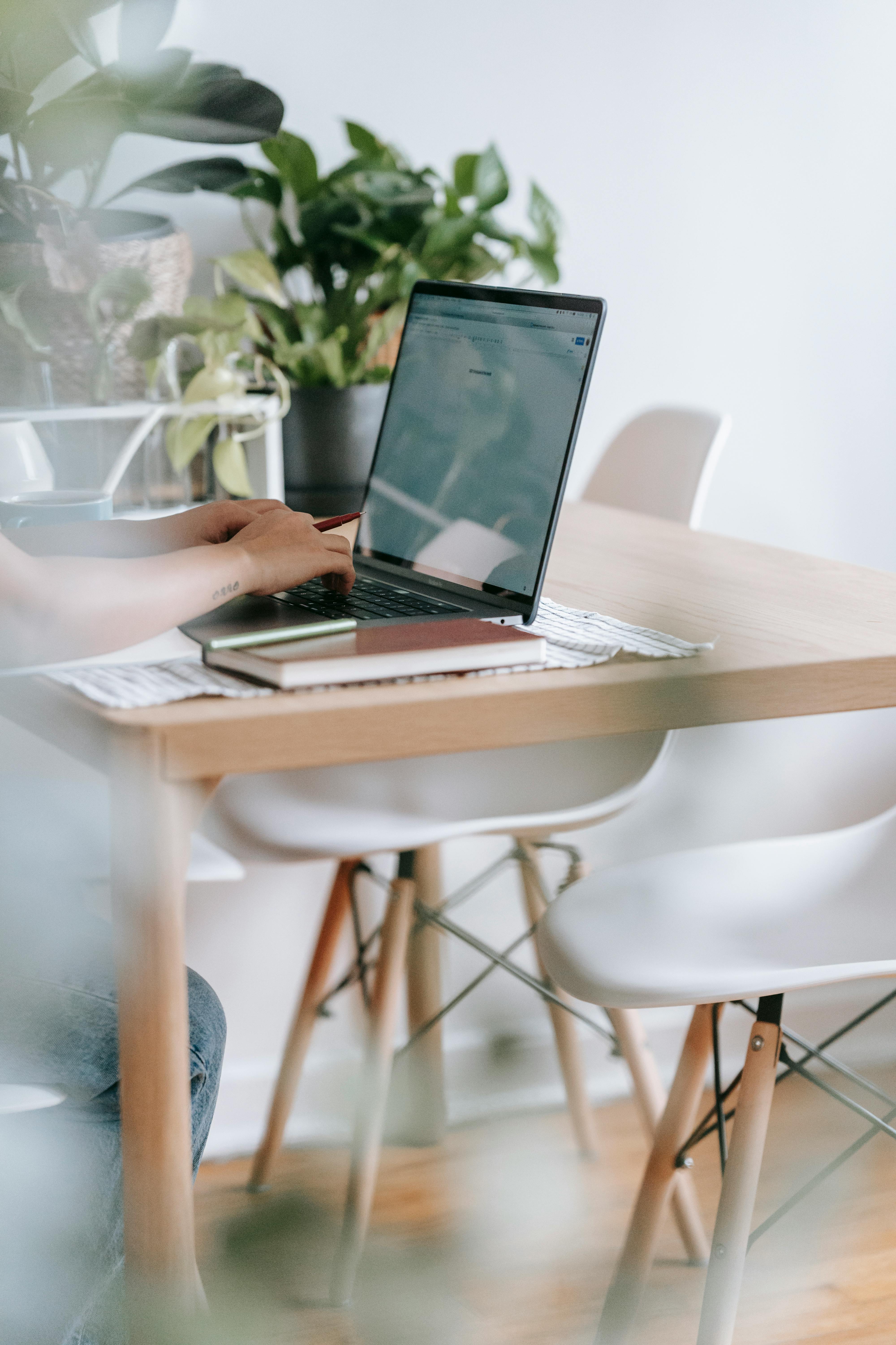 unrecognizable worker typing on laptop at table with flowers