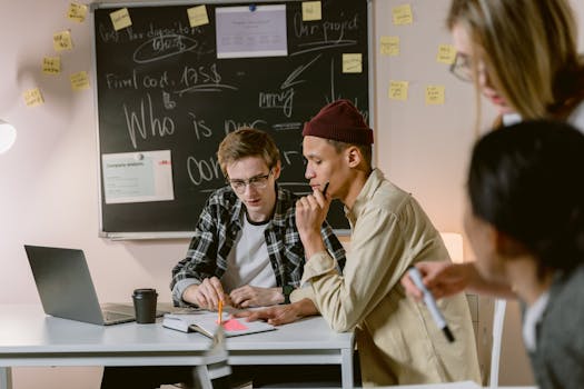Group of diverse colleagues brainstorming at a workspace with laptop and notes.