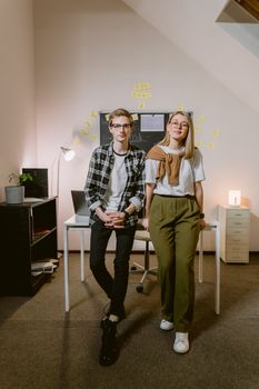 Two colleagues stand confidently in a modern office, embodying teamwork and innovation.