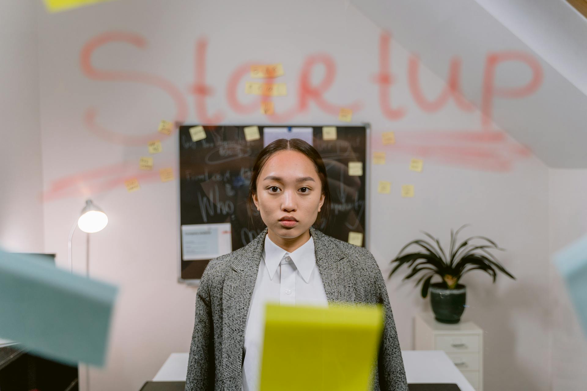 A young professional woman standing in a startup office with creative elements.