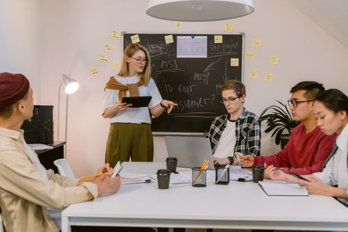 Free A diverse group of young professionals collaborating in a modern office setting with laptops and notes. Stock Photo