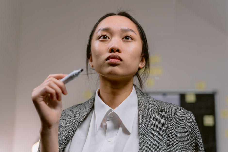 オフィスでマーカーを持つアジア人ビジネスウーマンが集中して考え込む様子。