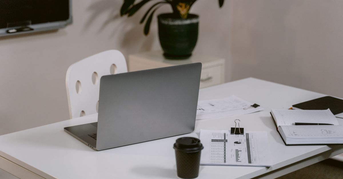 A minimalist desk setup with a plant, a notebook, and a coffee cup — no clutter, no chaos