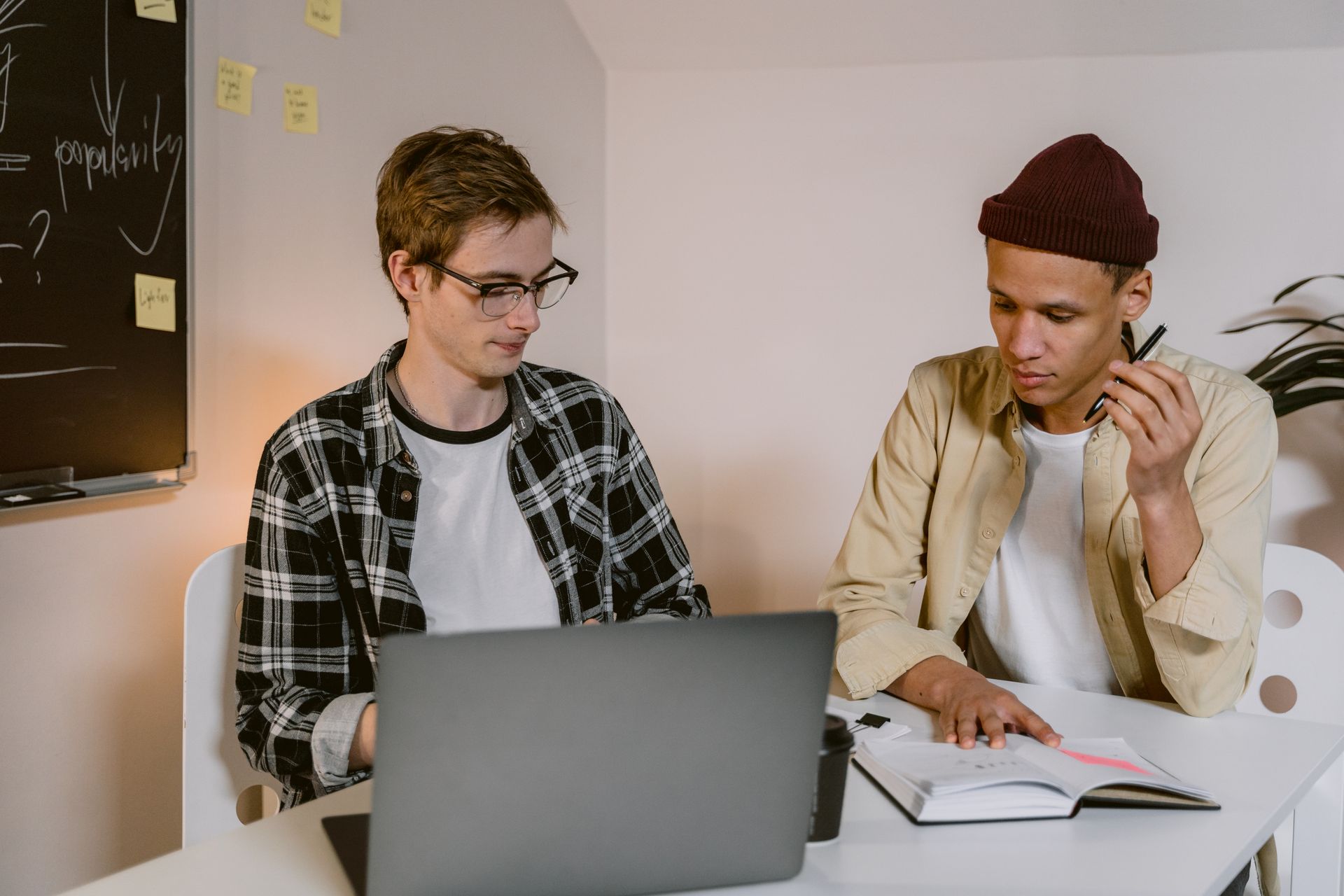 Two young colleagues working together at a laptop in a modern office setting.