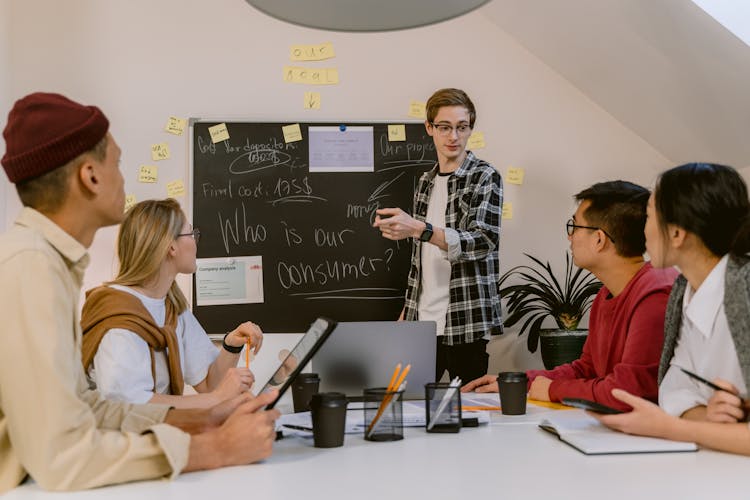 Man In Plaid Long Sleeve Shirt Presenting In A Meeting